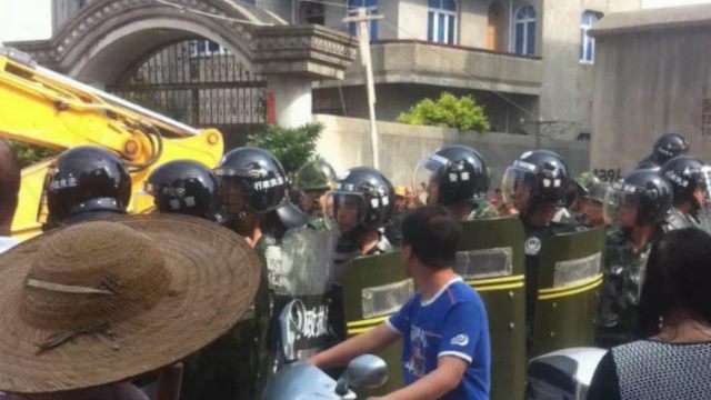 Fully-armed police officers block Christians protesting the demolition.