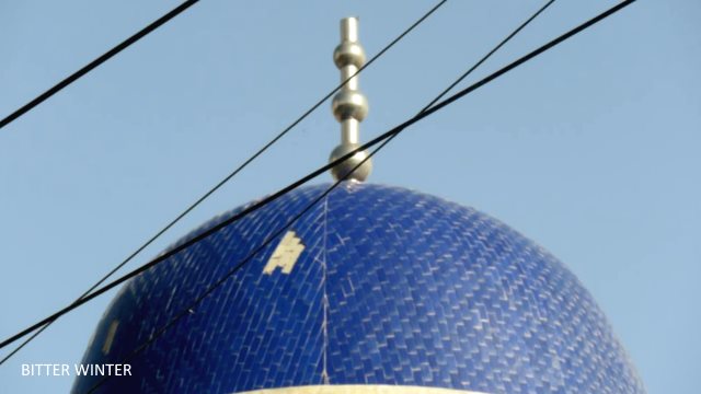 The crescent moon and star symbol atop the mosque across from Huiwangfu in the Yizhou Area of Kumul city has disappeared without a trace.