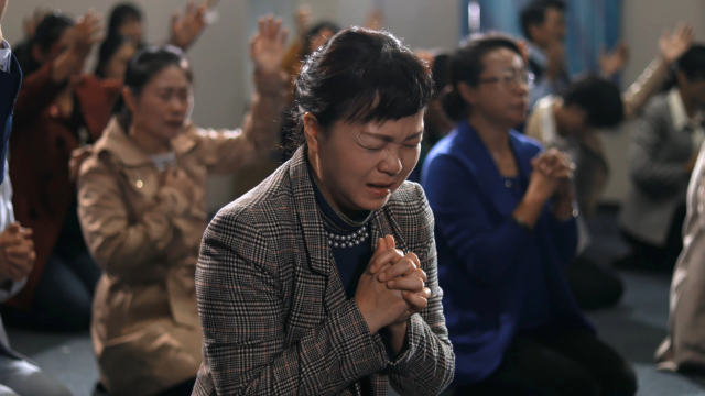 Believers at a house church are praying earnestly