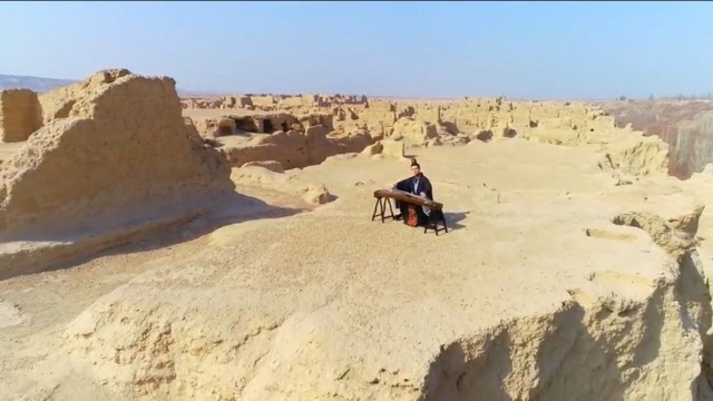 A Han Chinese musician playing the gu zheng on a plateau in the ancient city of Jiaohe, Turpan, during Uyghur festivities to celebrate the beginning of Spring.
