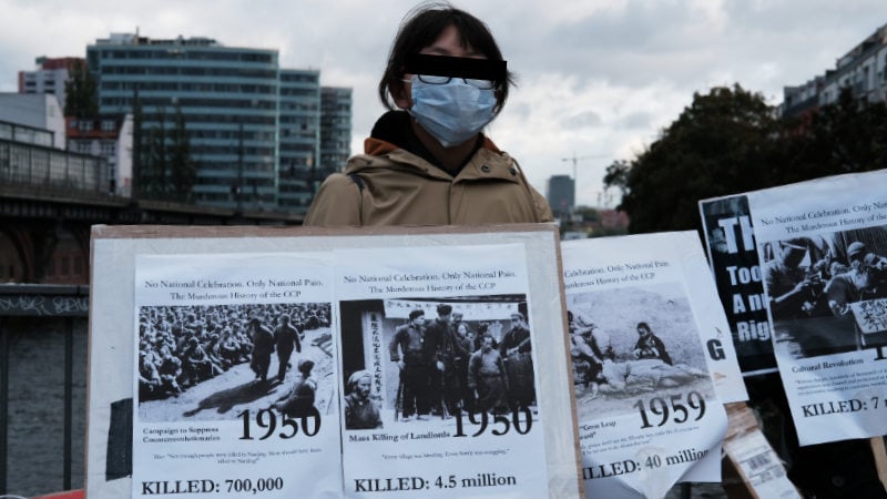 A young girl displays statistics on the number of Chinese people slaughtered by the CCP since it came to power.