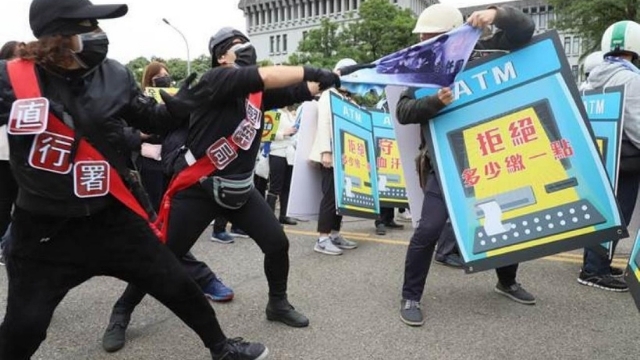 Protesters enact a mock attack on the human ATMs.