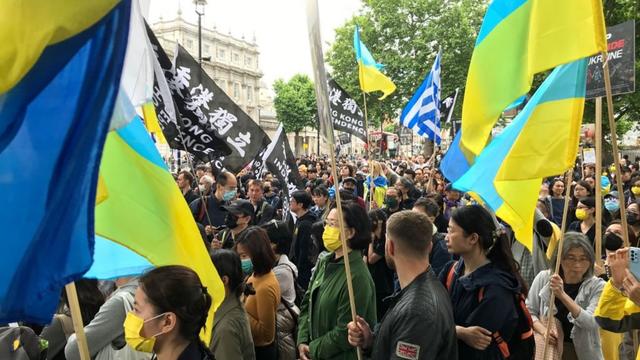 Chinese protesters unite with those from Ukraine as the UK government's Ukrainian flag flutters from the roof of Whitehall in the distance.