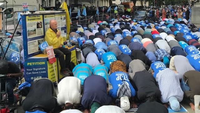 法輪功の代表者が見守る中、ロンドンの中国大使館の外で抗議活動中に祈るイスラム教徒。 ルース・イングラムによる写真。