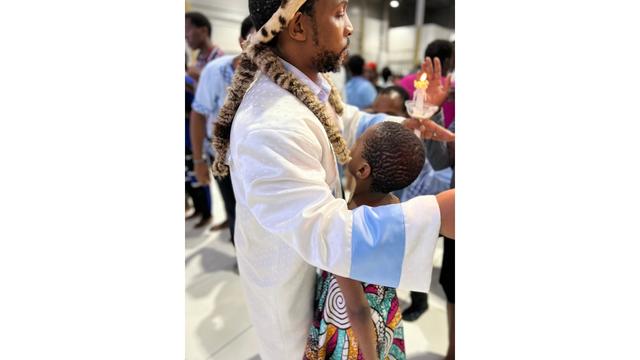 IMboni embraces a child during a Tuesday healing service. Photo by Massimo Introvigne.