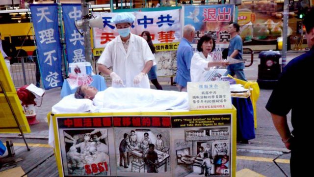 香港の法輪功学習者が臓器狩りがどのように行われるかを実演している。 クレジット。
