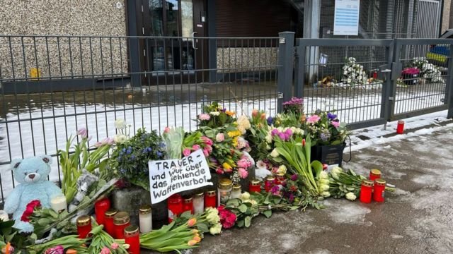 Flowers in front of the Kingdom Hall of Jehovah's Witnesses in Hamburg-Alsterdorf after the March 9, 2023, shooting, with a sign blaming the failure of the German gun control system for the tragedy. Credits.