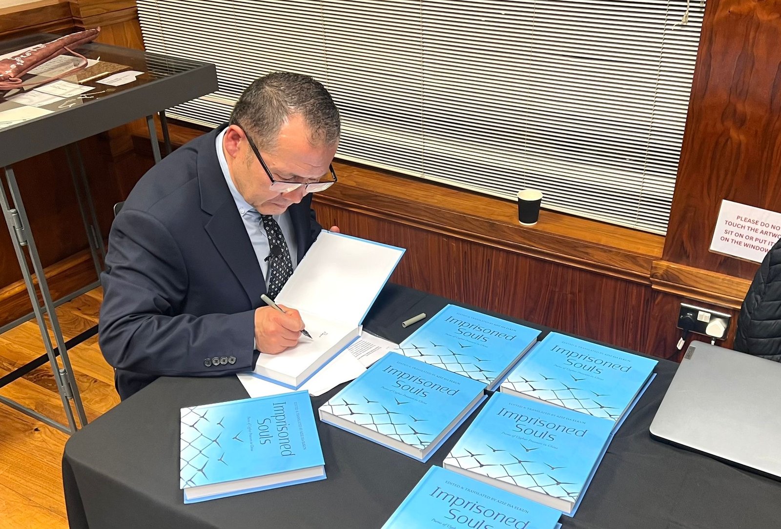 Aziz Isa Elkun signing copies of “Imprisoned Souls” at the launch event in London. Courtesy of Hertfordshire Press.