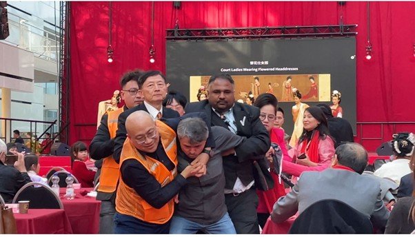 Chinese security personnel force the activist out of the room.