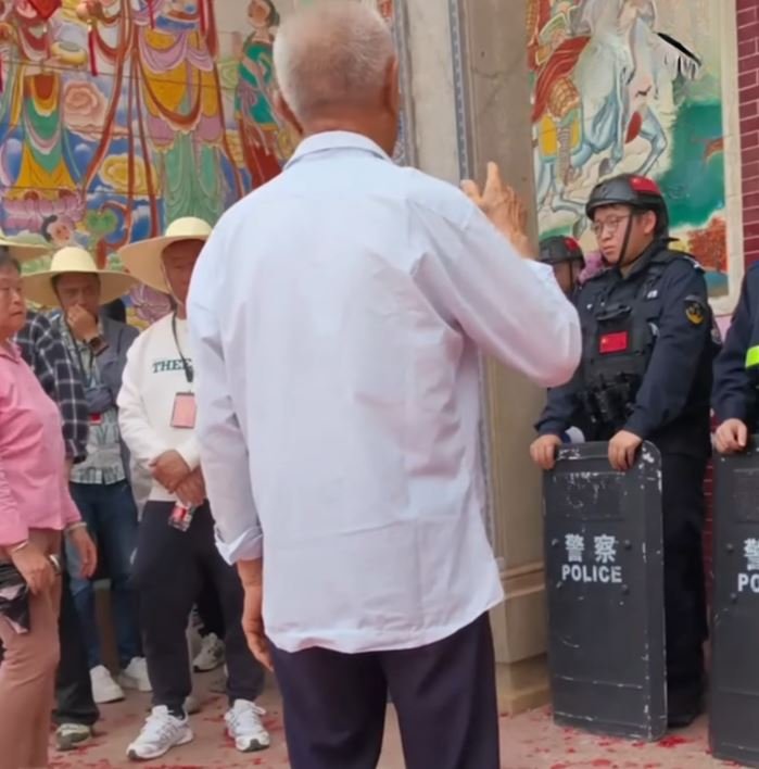 A villager confronts the police blocking the temple.