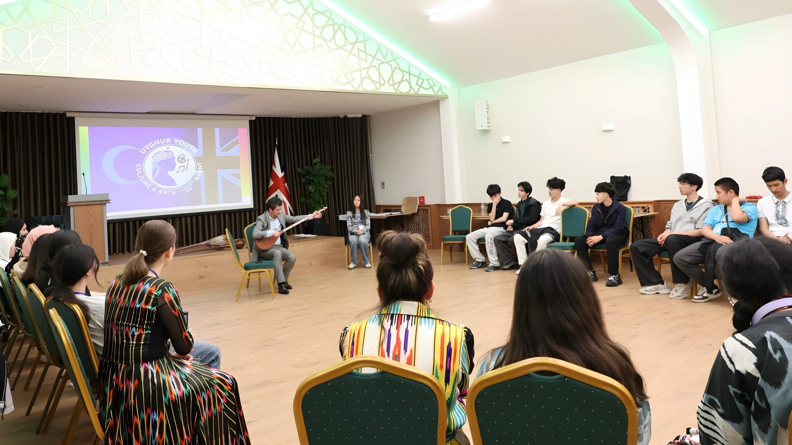 Music teacher Mirkamil Turkel demonstrating Uyghur traditional instruments to teenager Uyghurs at the recent Uyghur youth cultural event in London. Photo used with permission of Mirkamil Turkel.