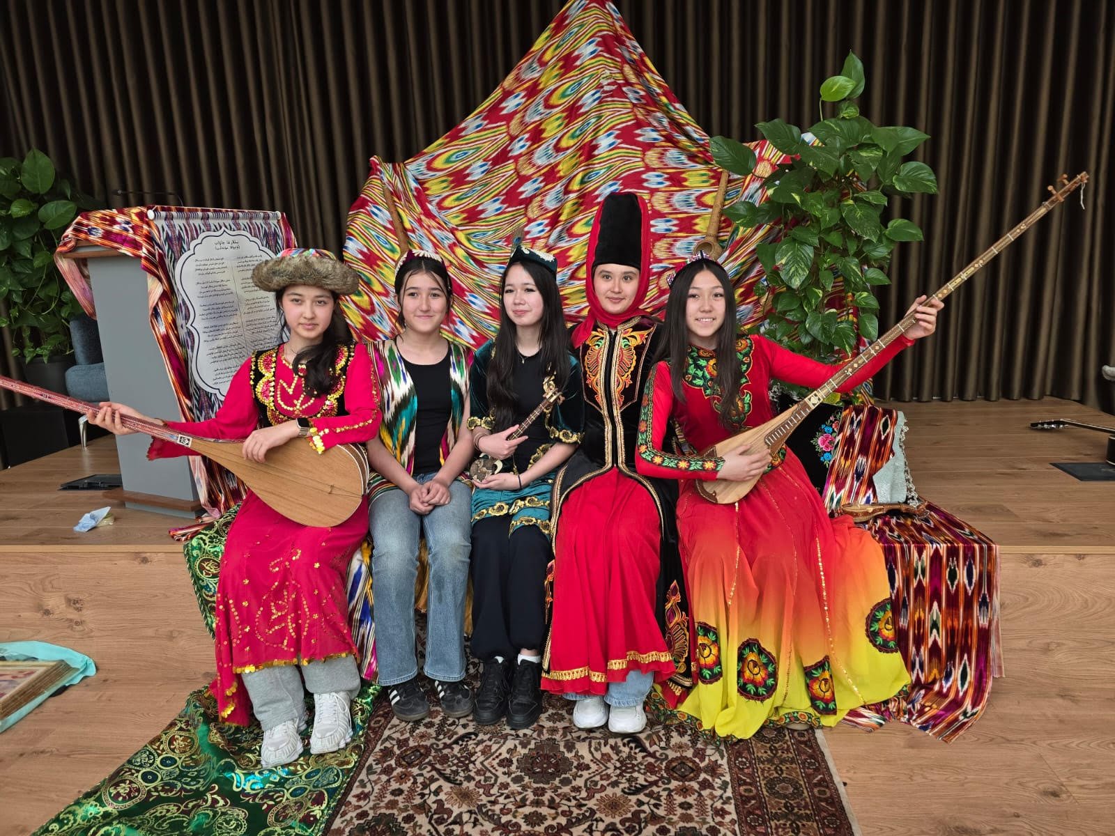 Uyghur diaspora teenage girls dressed in national costumes, trying out their traditional instruments. Photo courtesy of Mirkamil Turkel.